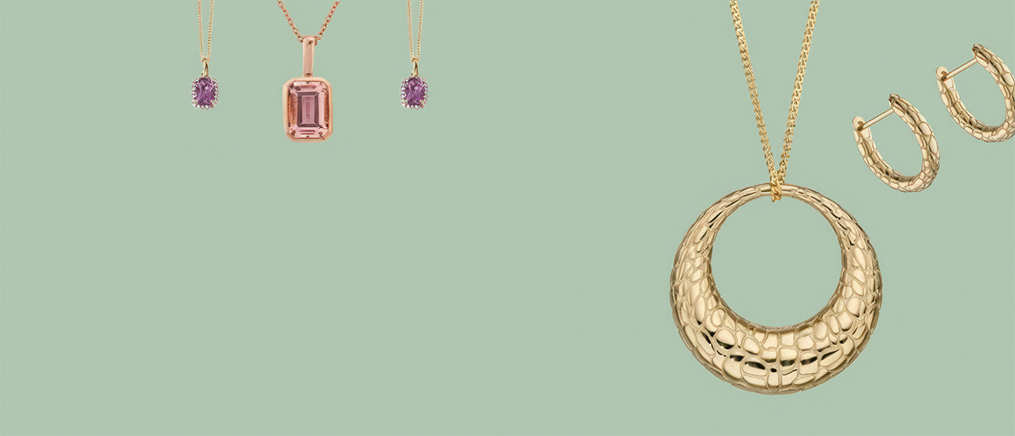 Gold jewelry including a necklace and earrings on a light green background